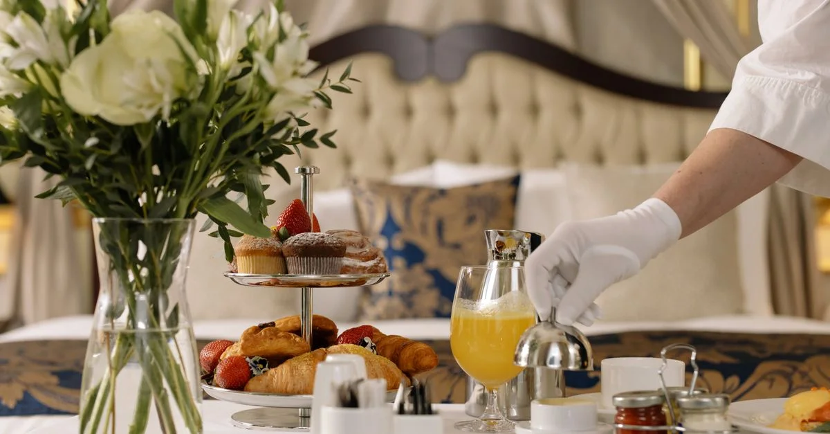Service d'étage luxueux d'hôtel avec des pâtisseries, du jus et des fleurs fraîches sur une table.