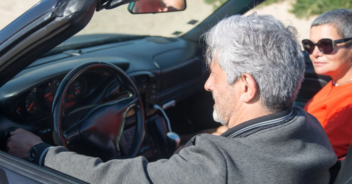 Un couple senior profitant d'une conduite ensoleillée dans une décapotable à travers le Portugal pittoresque.