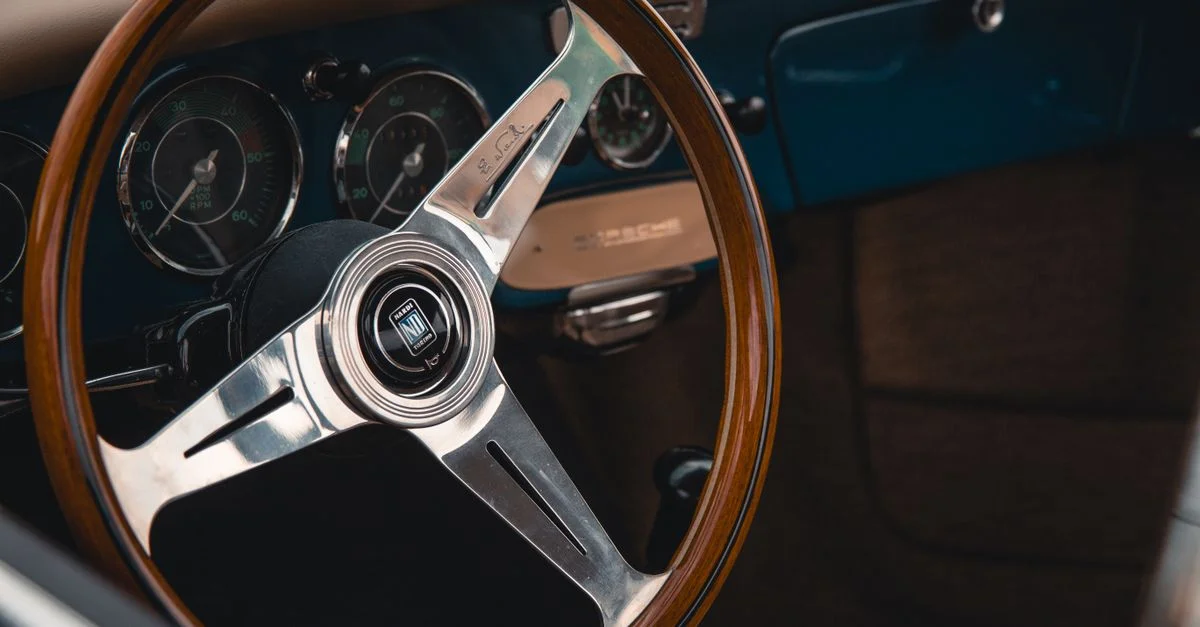 Gros plan sur un volant et un tableau de bord de voiture vintage, mettant en avant le design automobile classique.
