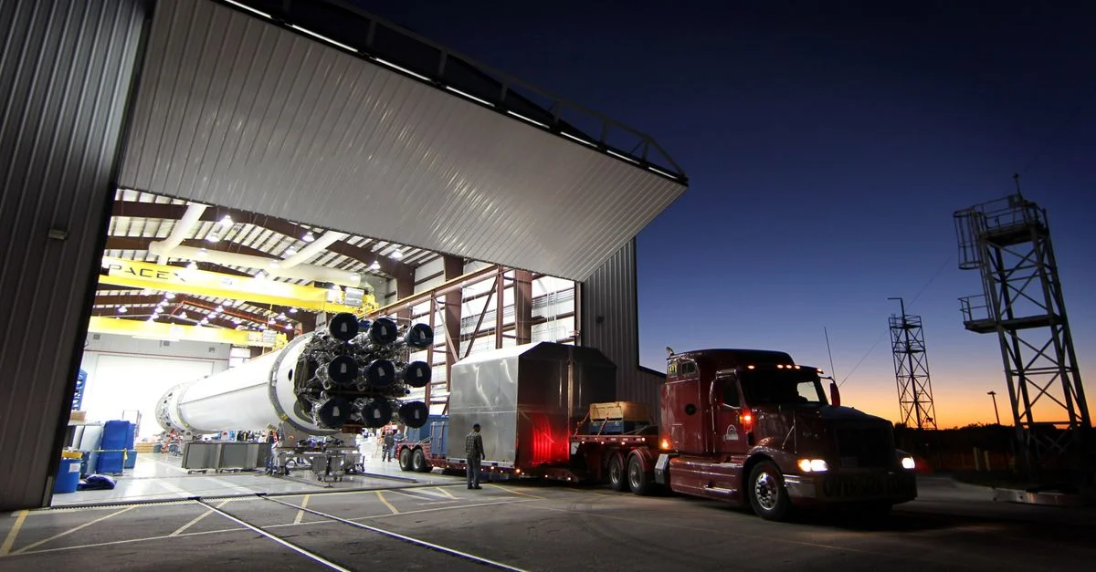 Une grande fusée en cours de déplacement d'un hangar au crépuscule, mettant en valeur l'ingénierie avancée et la technologie spatiale.