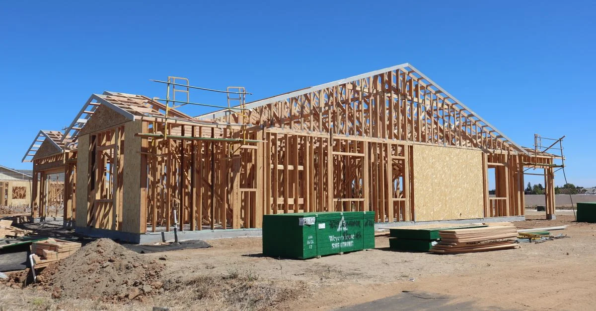 Construction d'une maison à ossature bois sous un ciel bleu azur, par une journée ensoleillée.