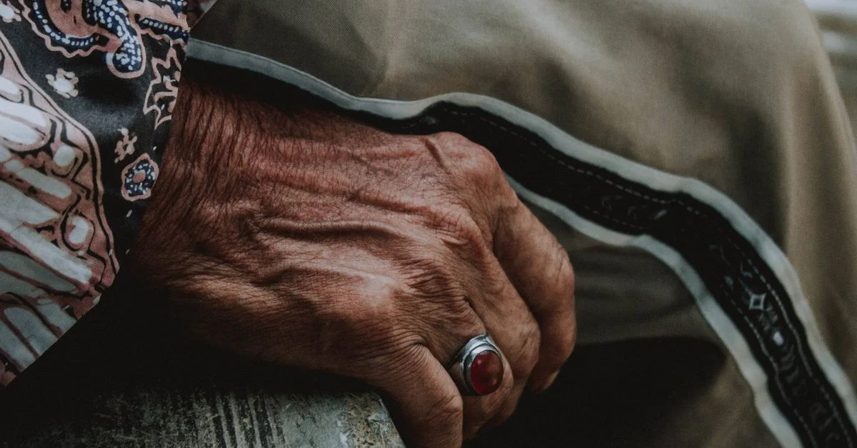 Gros plan sur la main d'un senior portant une bague, avec un vêtement traditionnel indonésien.